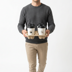 Homme transportant quatre cafés dans un porte-gobelets en carton, gobelets blancs et couvercles noirs