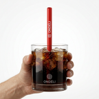 Paille Frozen rouge personnalisée dans un verre de cola tenu à la main sur fond blanc